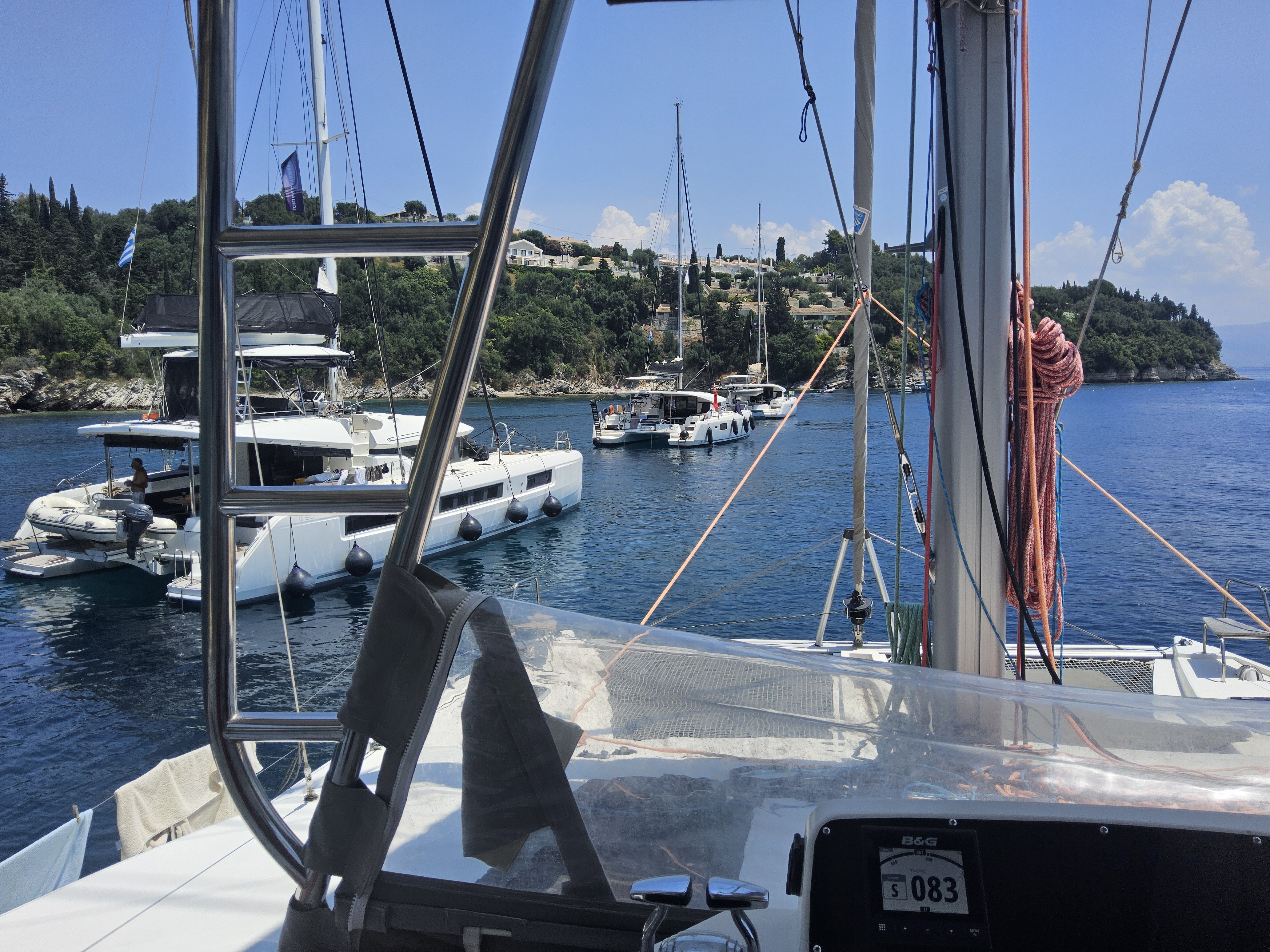 Catamaran rafted in a sheltered Mediterranean harbour with working nav instruments and flag