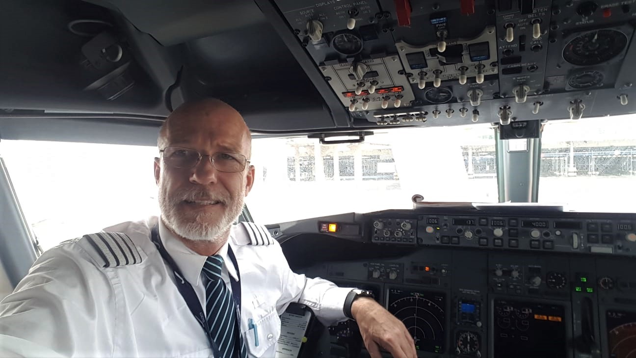 Daniel Giessler in airline captain uniform inside a commercial cockpit